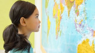 A girl looking at a world map in a classroom.
