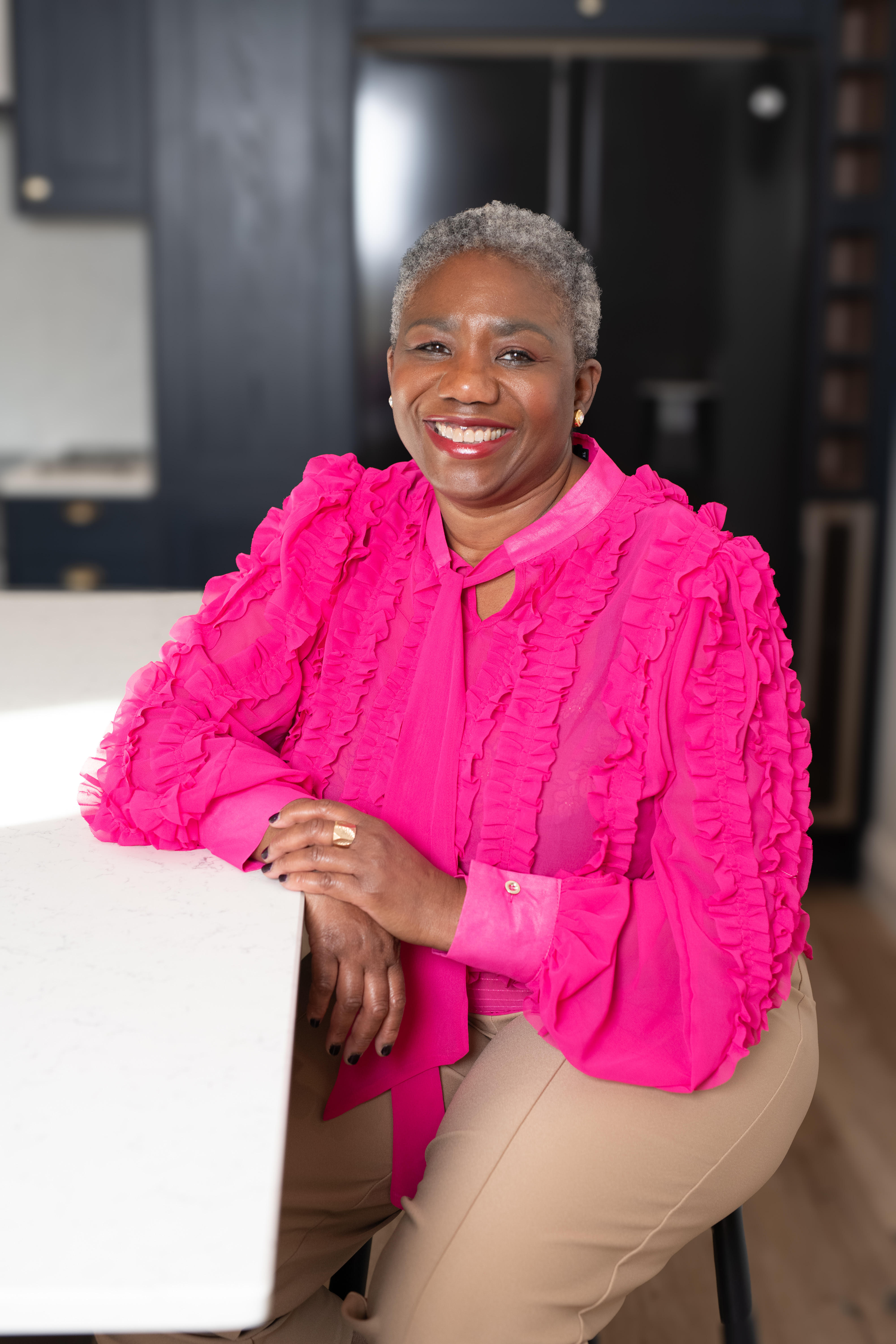 Freelance beauty writer and makeup artist Joyce Connor pictured wearing a pink ruffled blouse, sitting at a marble table