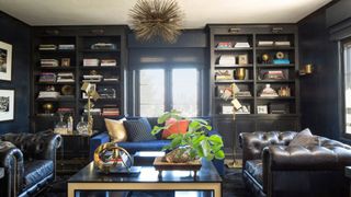 home library with blue walls and bookcases, leather chairs
