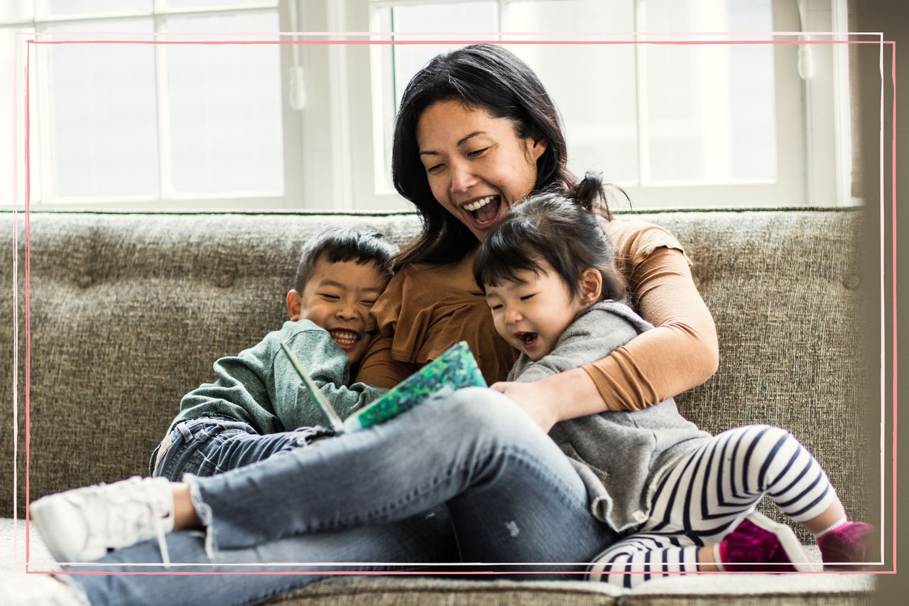 A mum reading to two young children on a sofa