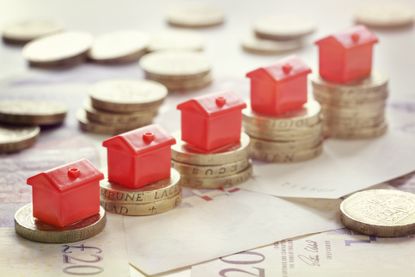 buy to let mortgages: Small red houses balanced on top of pound coins