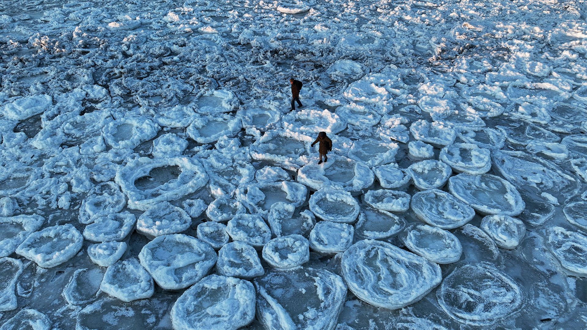 
                                People walk across "pancake ice" formations in the Baltic Sea near Mikoszewo, Poland
                            
