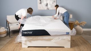 Our two sleep staff writers remove the plastic shipping materials from the outside of the Nectar Classic Memory Foam Mattress during testing