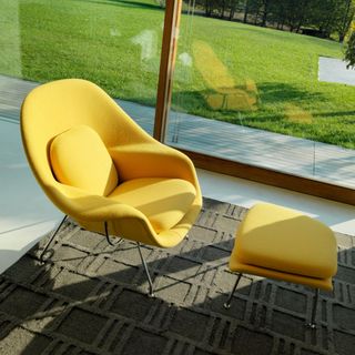 Yellow Knoll Saarinen Womb Chair with matching Ottoman by window in living room