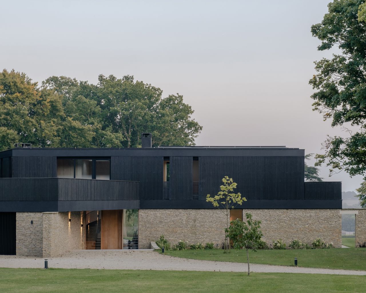 capability house, a rural retreat with clean contemporary lines, stone walls and a black wood top set among green expanses