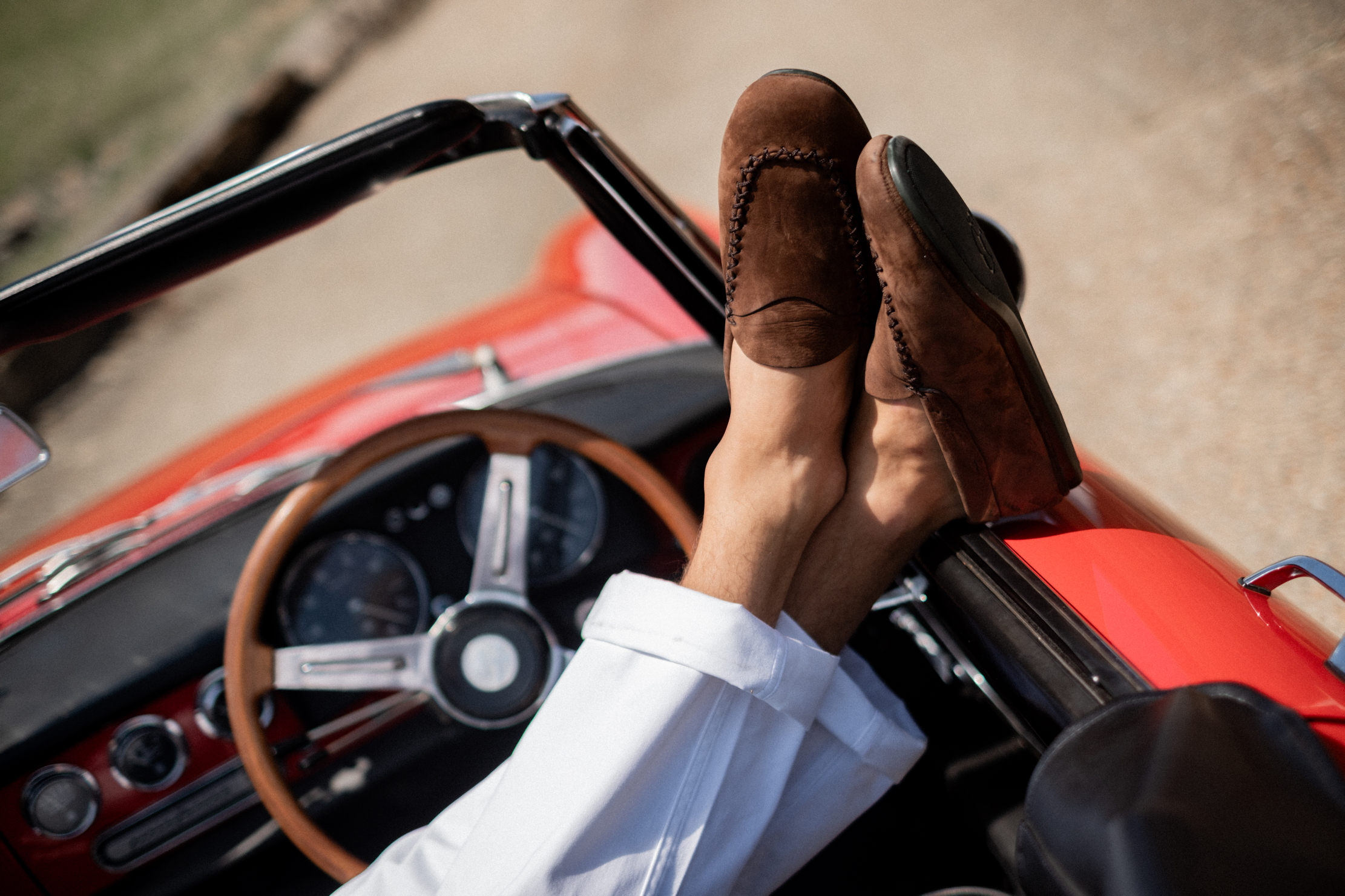 A man wears a pair of loafers in the car