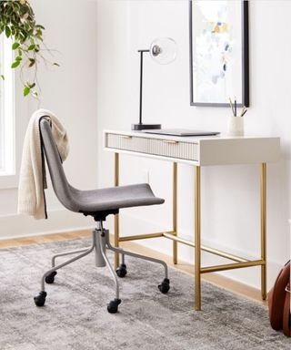 A white and gold desk with a gray office chair next to it