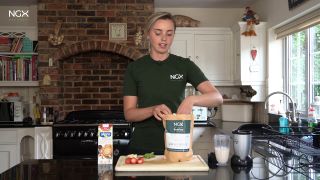 prYoung woman preparing a protein shake in a kitchen