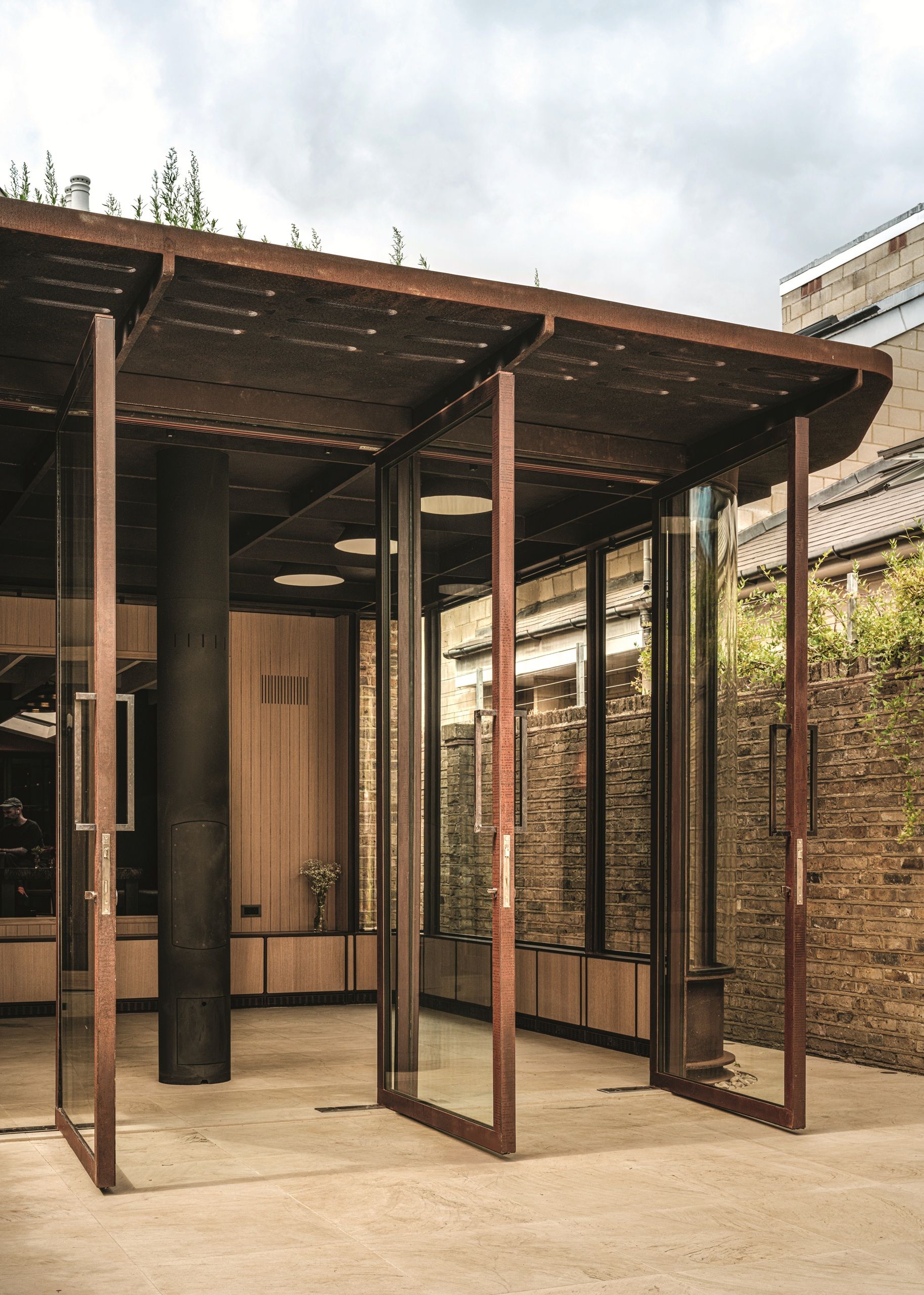 modern extension with tall timber-and-glass doors, tiled floor, timber panelled walls, and low cabinets