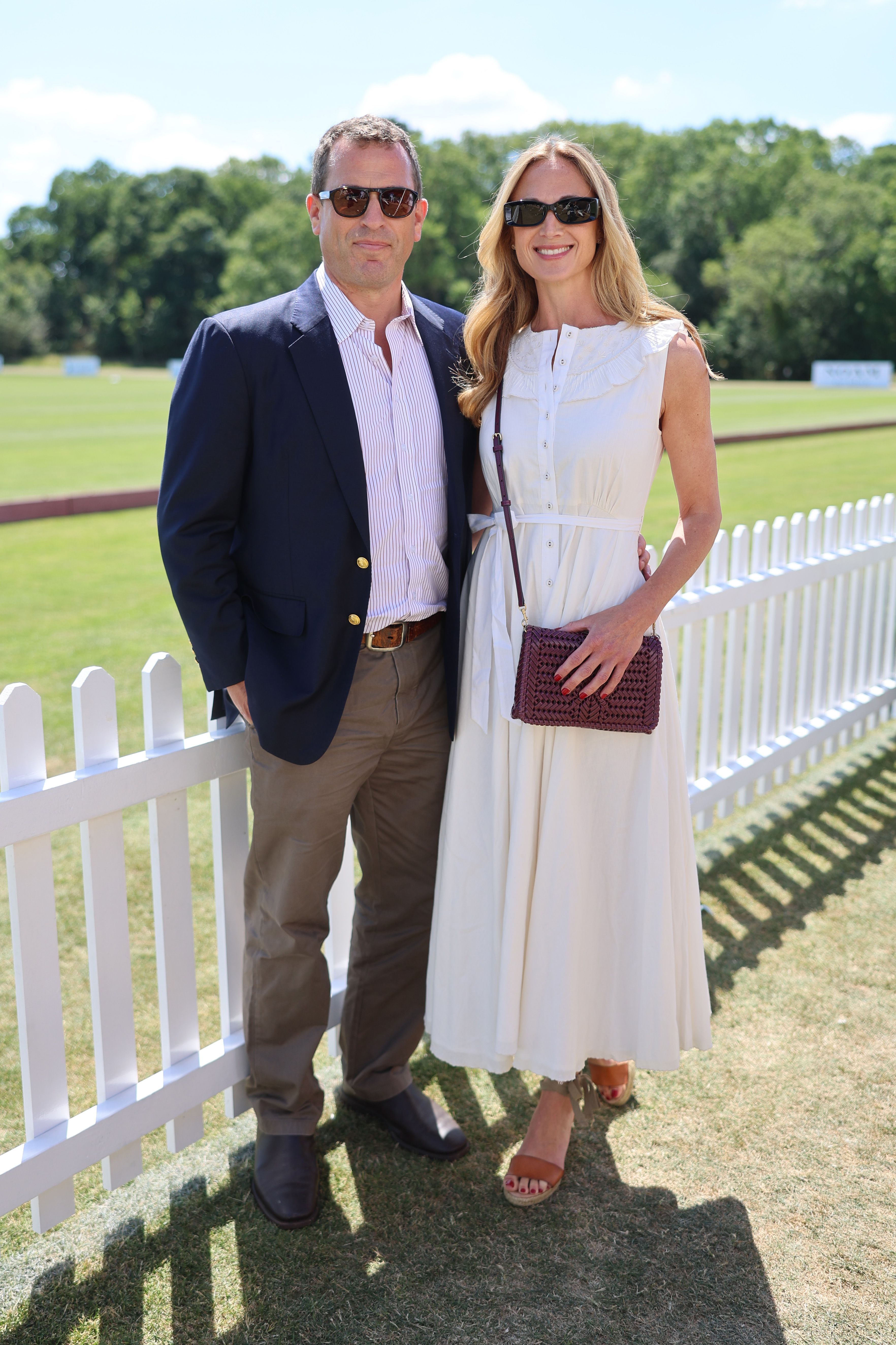 Harriet Sperling wearing a white dress next to Peter Phillips, standing against a white fence
