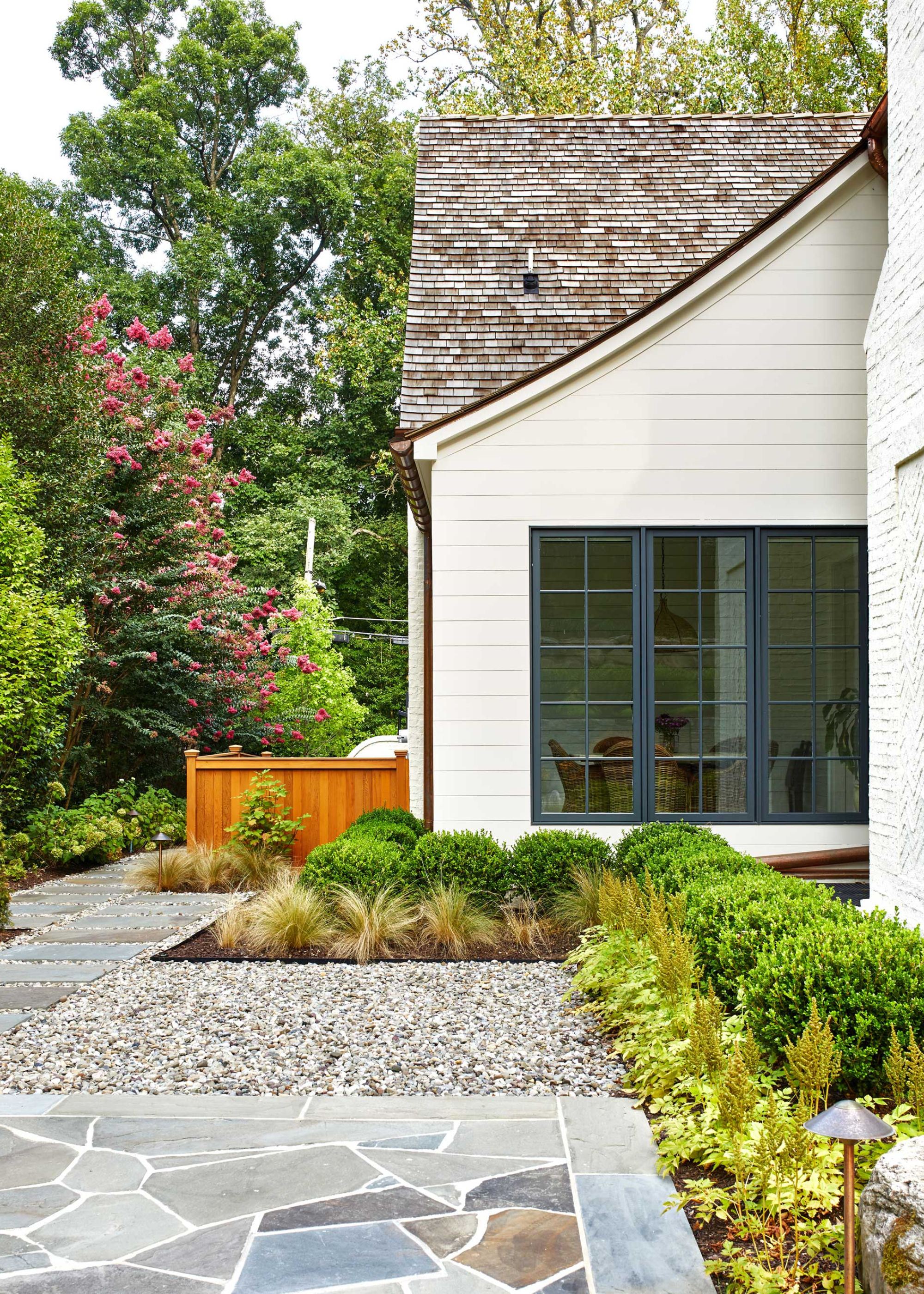 a side yard with gravel and paving as well as plants placed neatly on one side of the paving