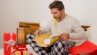 Man wrapping a gift on bed
