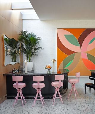 Home bar with pink stools and a black curved bar