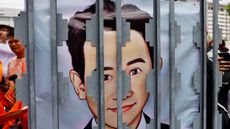 A banner featuring an image of Pita Limjaroenrat behind bars