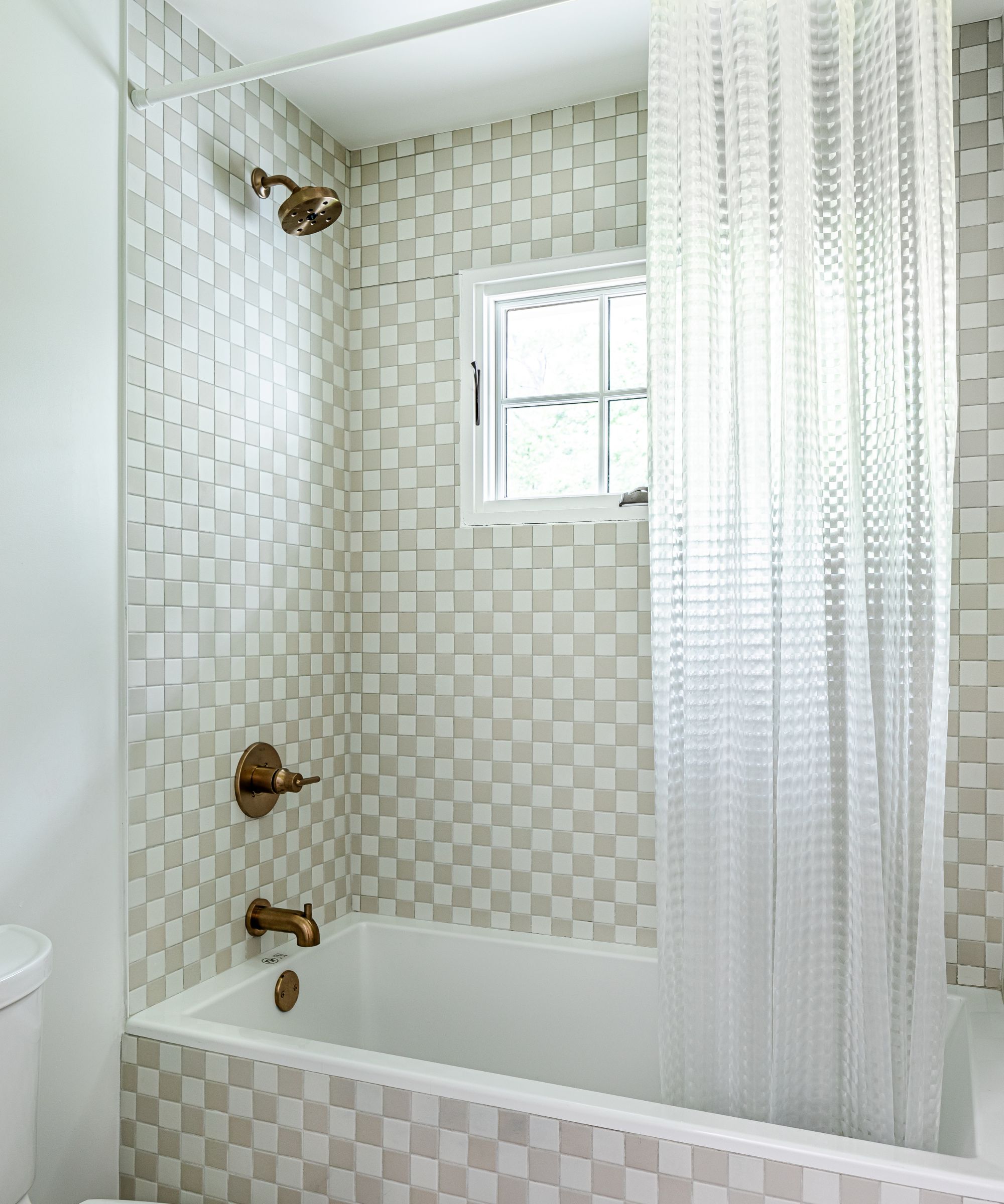 A kids&#039; bathroom decorated in Sherwin-Williams Decorator&#039;s White paired with white and beige checkerboard tiles in the shower area