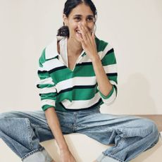 A model wearing a green, white and black striped top and jeans from THE OUTNET. 