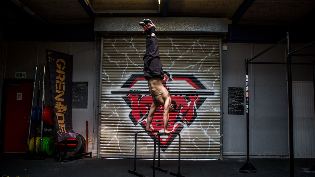 Jase performing a handstand holding on to two bars