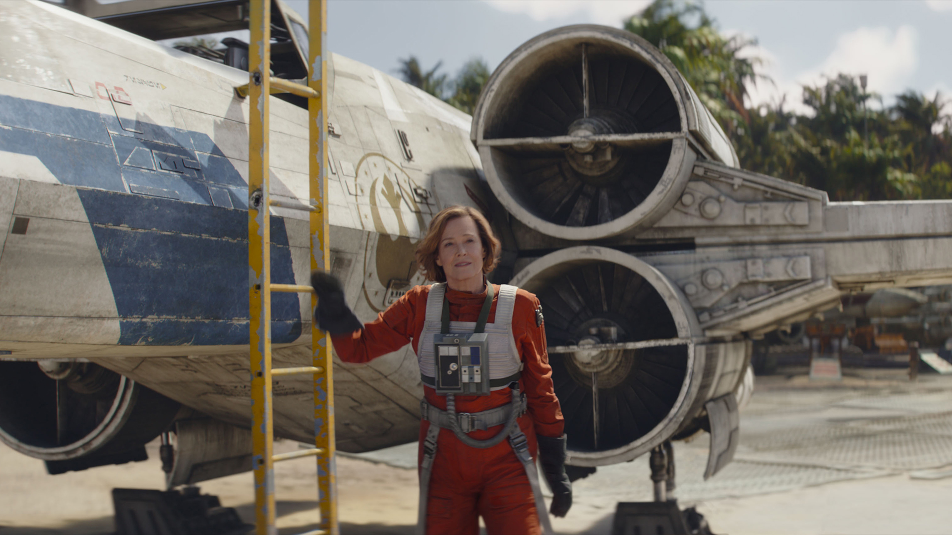 Sigourney Weaver's Colonel Ward hangs on a ladder next to an X-Wing in The Mandalorian and Grogu