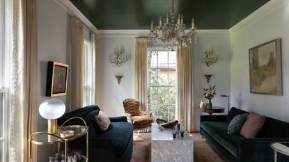 earth tone living room with green painted ceiling, green sofas, earth-toned curtains, antique furniture, marble coffee table