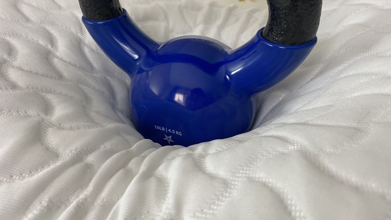A closeup of a 10lb kettlebell resting on the center of the Tempur-Pedic Tempur-Cloud Pillow. It has sank far into the surface, demonstrating pressure relief.