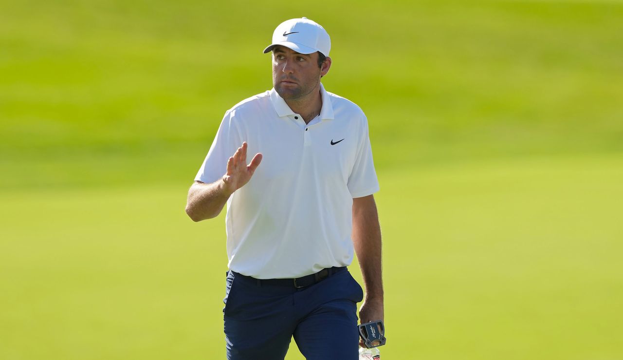 Scottie Scheffler waves to the crowd as he walks up the fairway