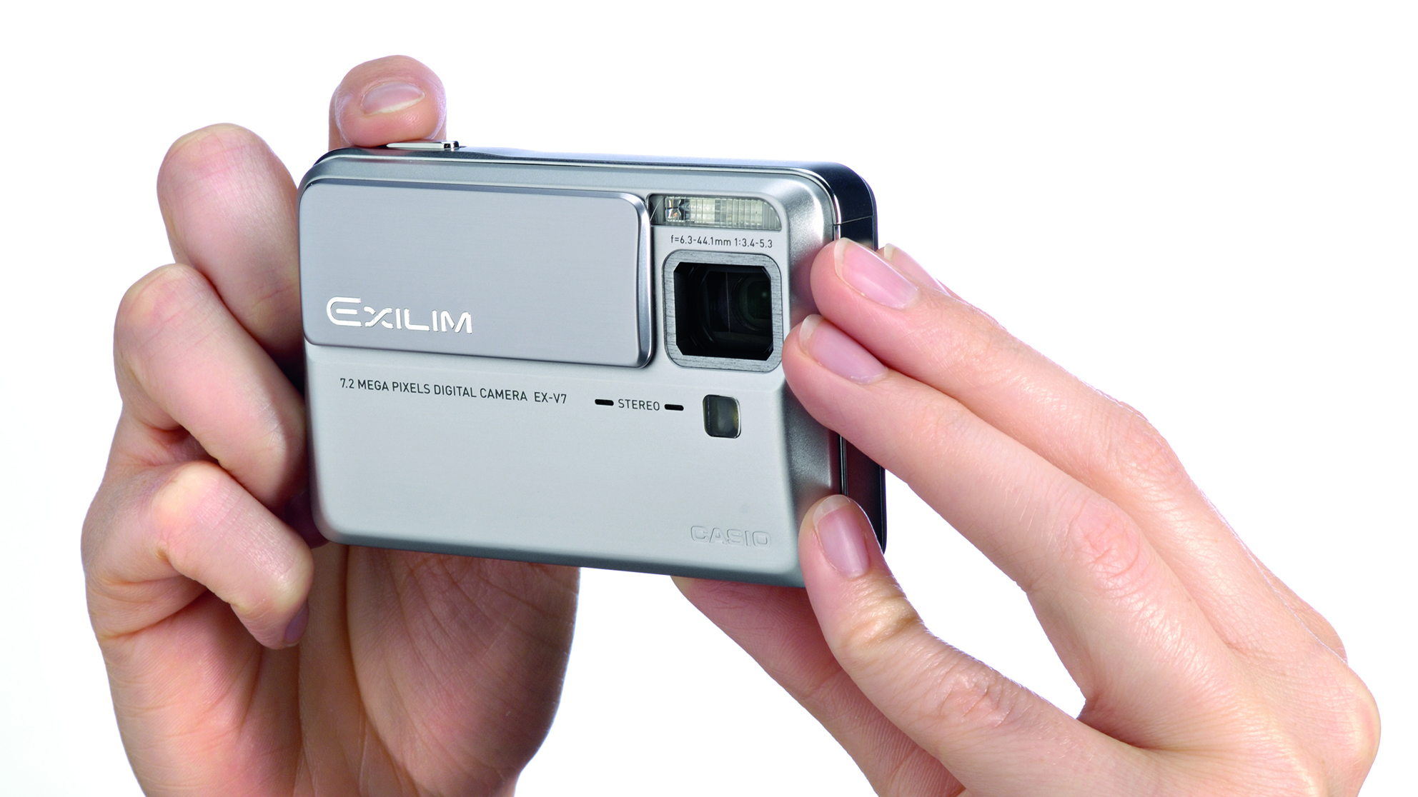 Casio Exilim EX-V7: Two hands are holding a silver digital camera with a lens in the top right. The brand &amp;quot;Exilim&amp;quot; and &amp;quot;7.2 megapixels&amp;quot; are visible on the camera's front