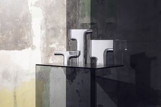 Silver vase designs by Nendo for Georg Jenson on plinth against rough wall background