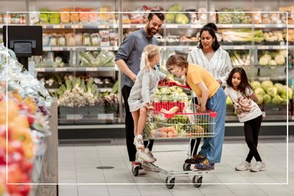 Happy parents with three children, pushing a trolley in a supermarket