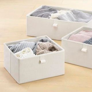 White pull-out bins for under the sofa filled with clothes