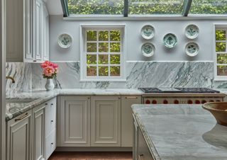 A white kitchen with marble countertop and backsplash