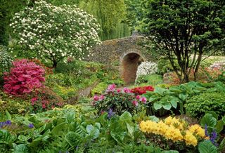 The Dell Garden, Bressingham, Norfolk. The flint bridge was built by Alan Bloom with mixed borders with perennials, shrubs and bulbs either side. Picture: Richard Bloom