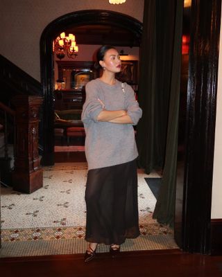  @mimixn wears a chic winter outfit with a long sheer skirt and oversize sweater with heels and red lipstick in NYC.