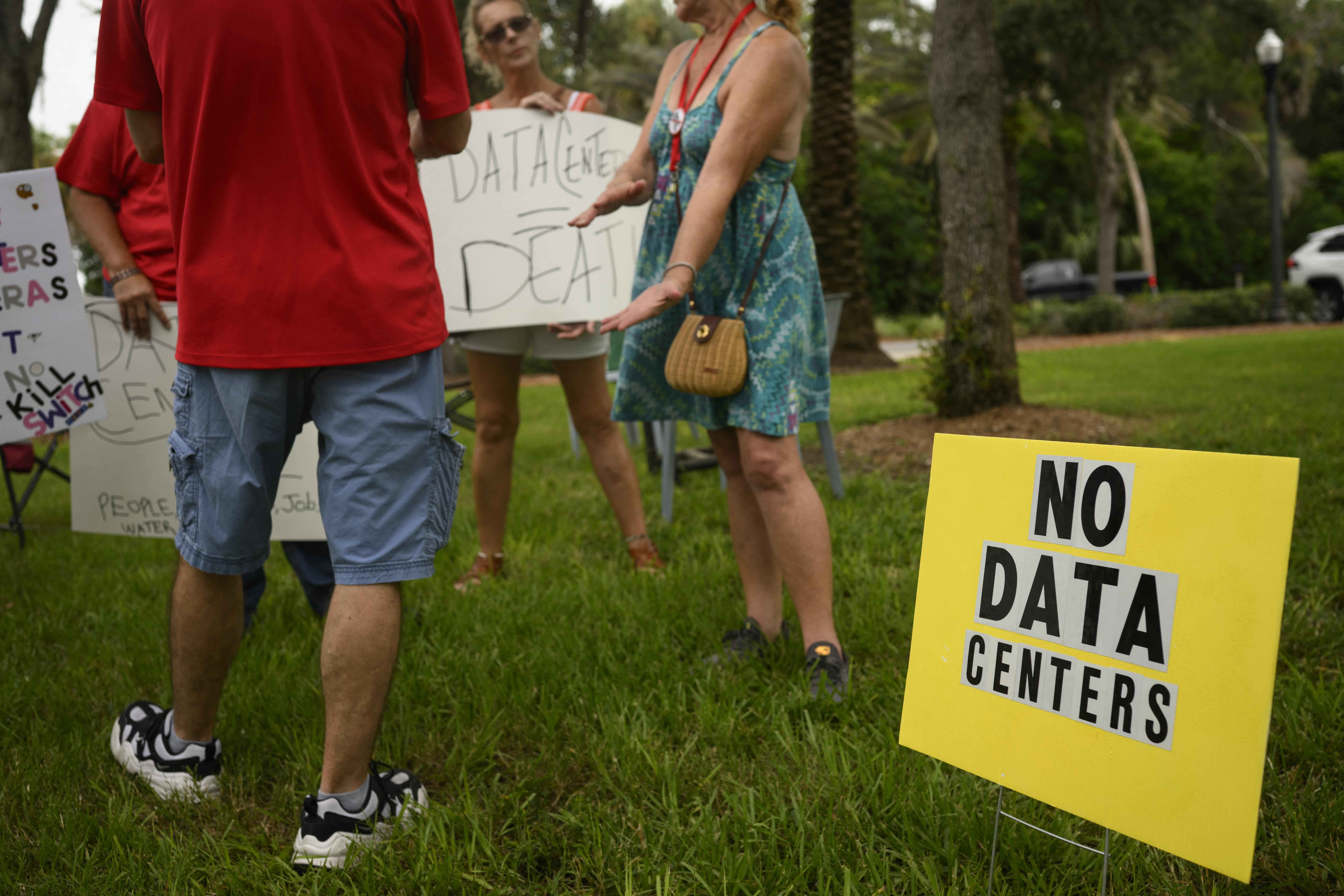 People hold signs during a nationwide protest against AI data center expansion outside Peace Hall in New Port Richey, Florida.