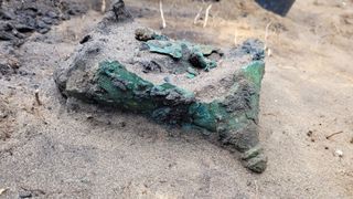 Fragments of a broken green helmet buried in the dirt