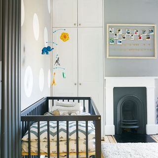 Monochrome nursery with white and light grey walls and a dark graphite grey cot