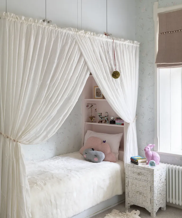 Kids room paint ideas with pale blue floral wallpaper and a recessed bed framed by white curtains