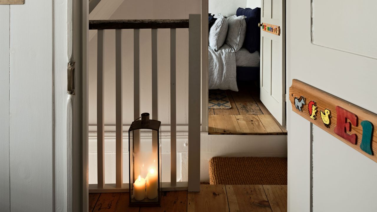 Open door looking into bedroom across hallway lit by lamp