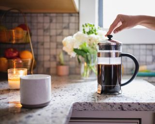 Coffee pot with coffee brewing, with mug and candle to the side, in a kitchen