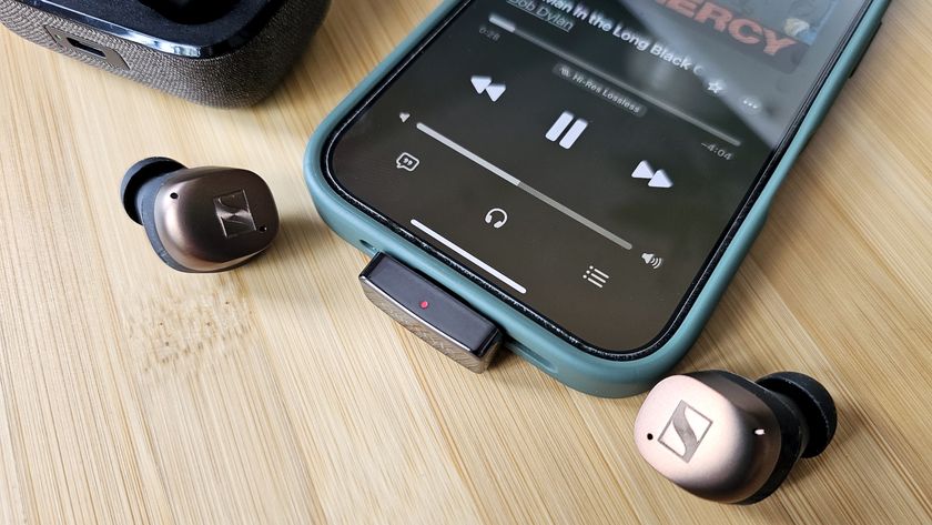 The Questyle QCC Dongle Pro with a smartphone to denote size, on a light wooden table