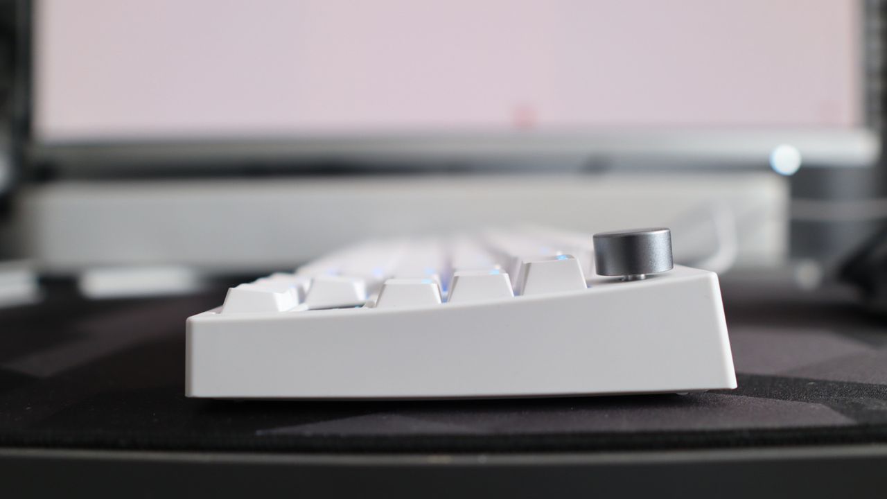 A Gamakay TK75HE gaming keyboard in white on a black and grey mouse pad with RGB lighting enabled.