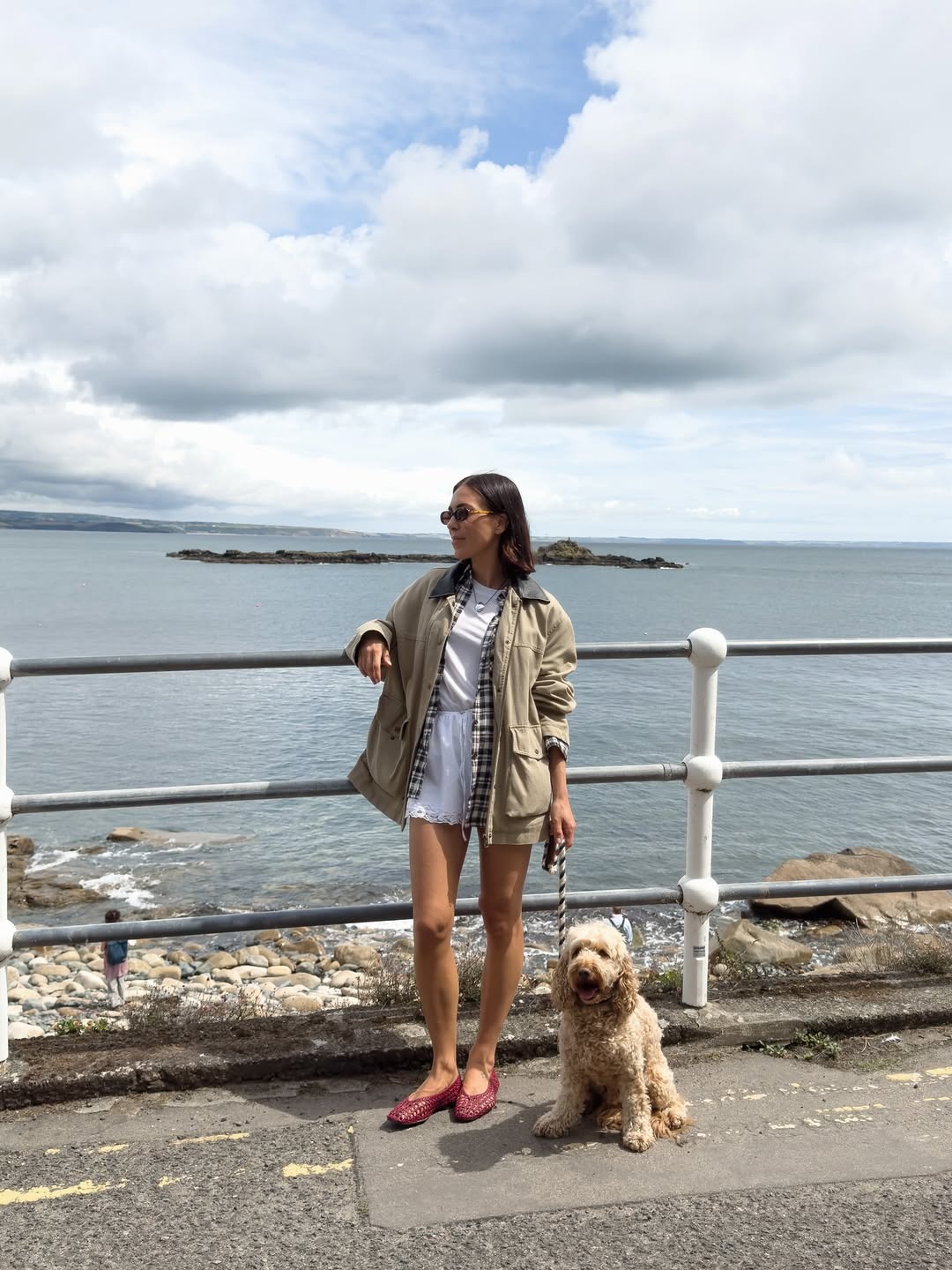 Influencer Jessica wears a beige jacket with a flannel, white crewneck, and lace-trim shorts.