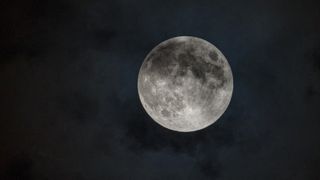 A bright full moon grows dark as it drifts into Earth's shadow during a penumbral lunar eclipse