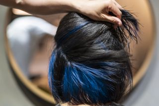 A woman with dyed hair, parted to show blue streaks underneath