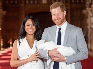 Prince Harry holding Archie with Meghan Markle by his side