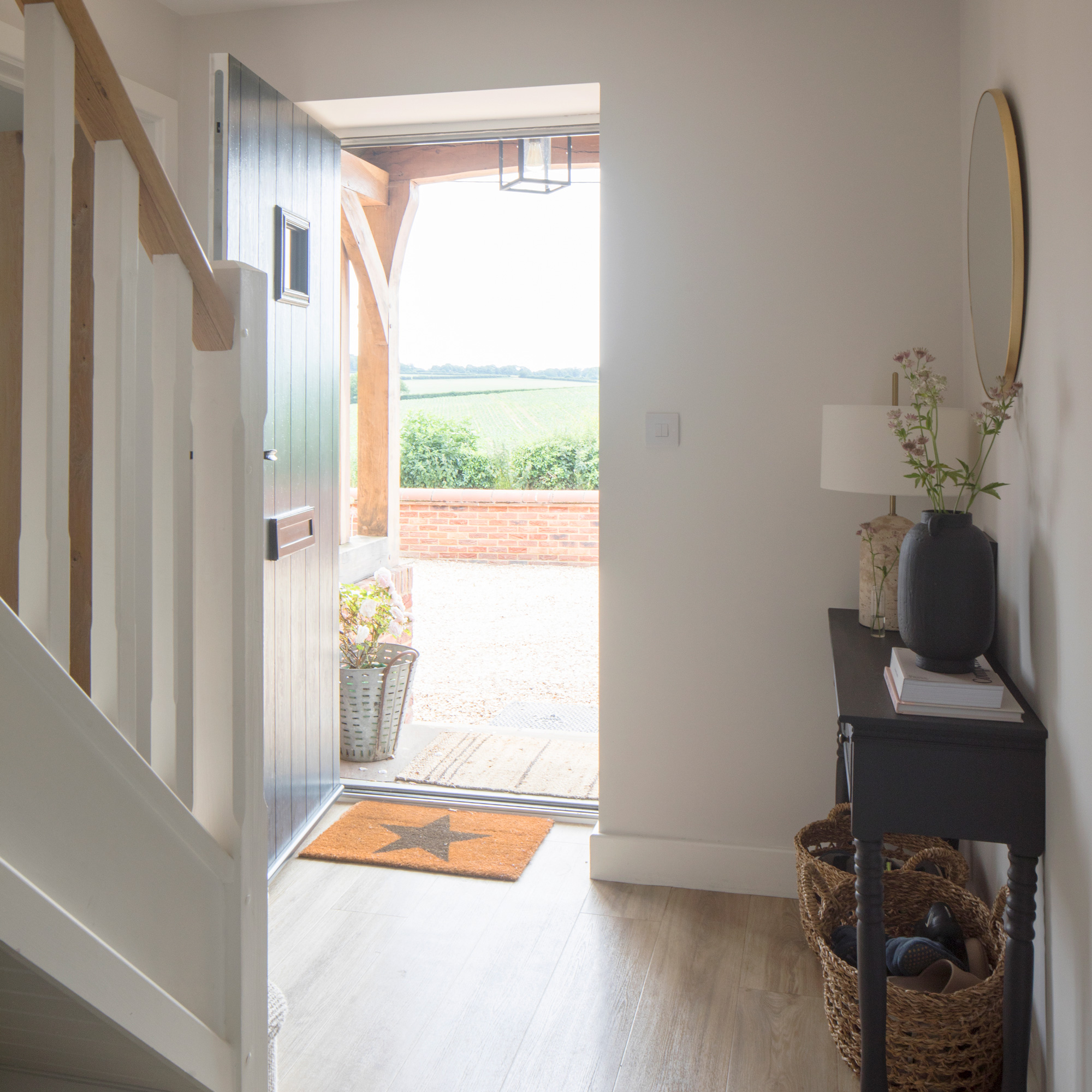 country cottage hallway with front door open, a doormat and console table