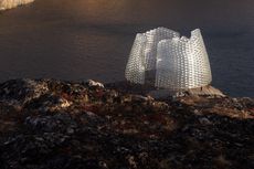 Day time image of the Konstantin Ikonomidis's pavilion located on the rocky terrain, back drop of water in the distance 