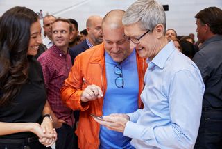 Jony Ive stands next to Tim Cook and points at an iPhone at an Apple event.