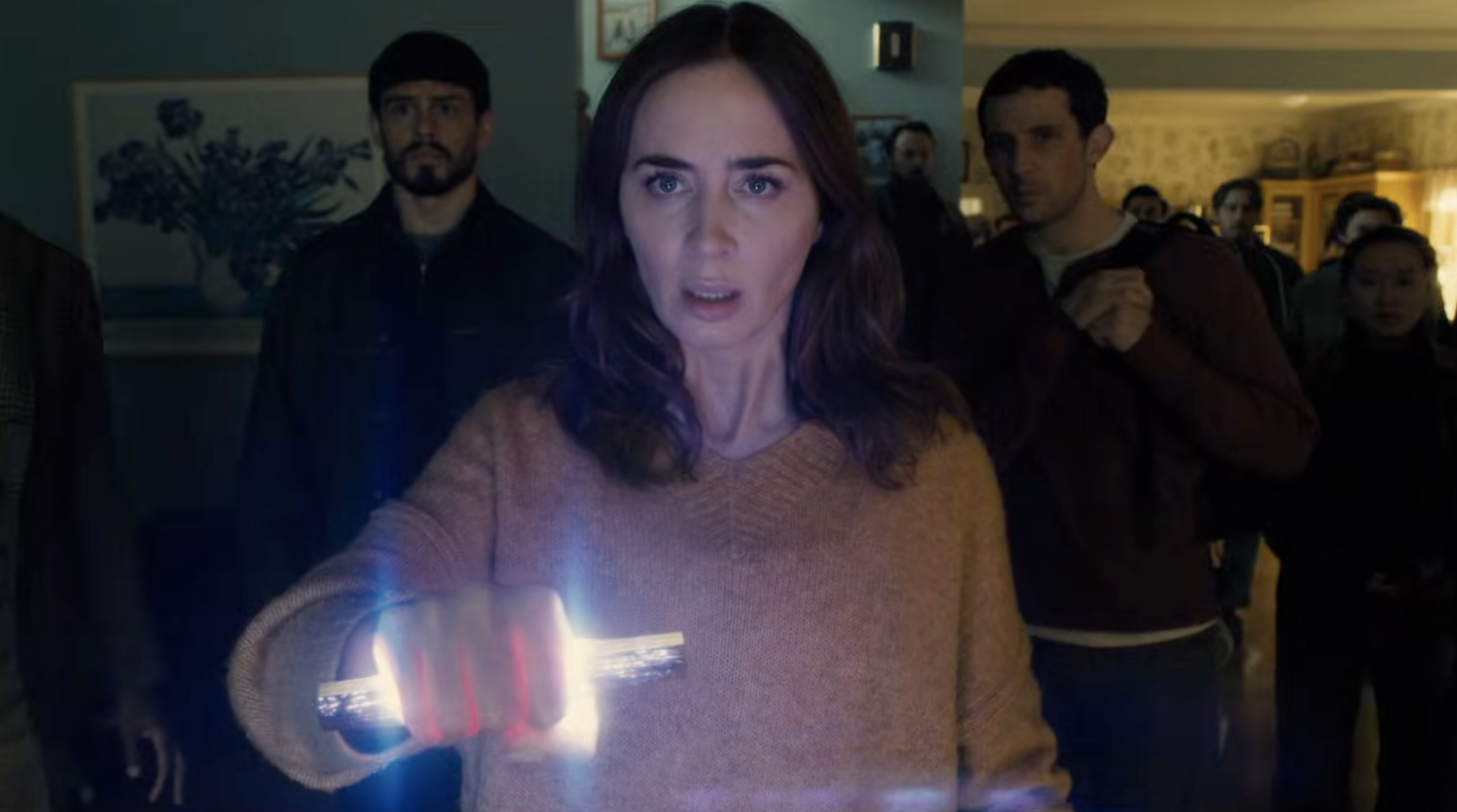 Emily Blunt holding a piece of alien technology with Josh O'Connor standing in the backroom.