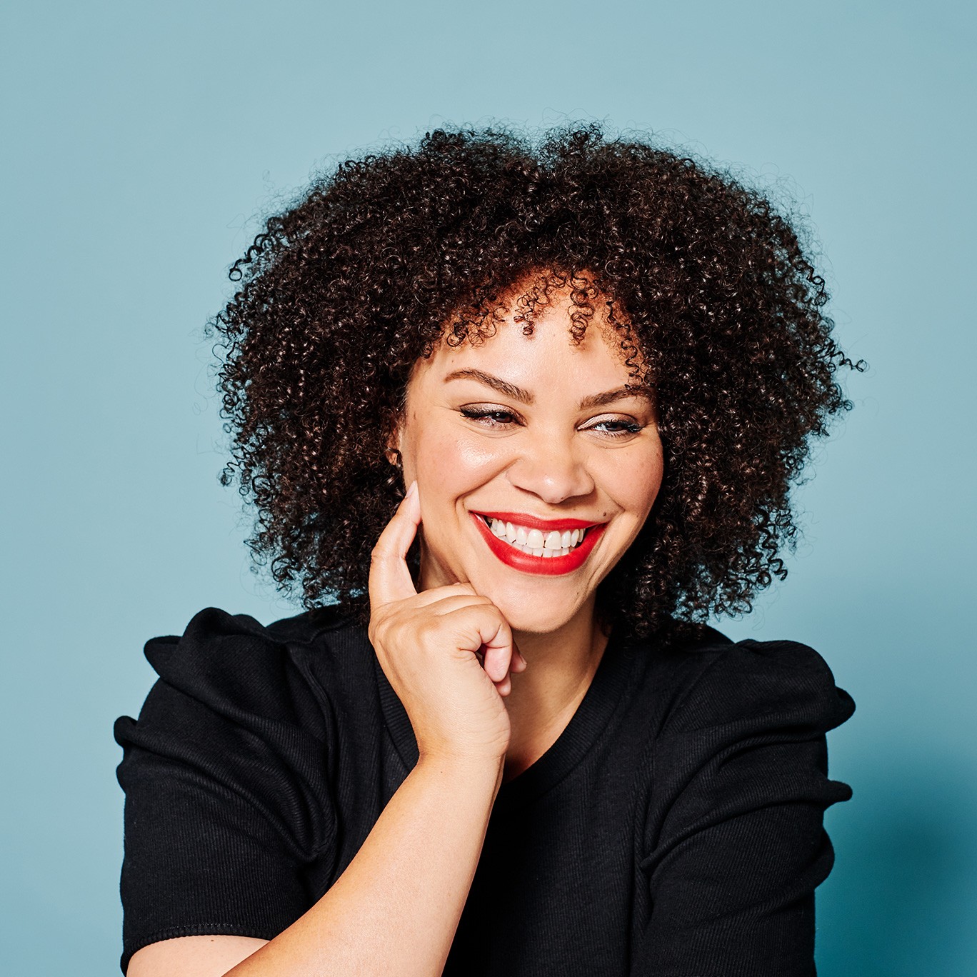 Renee Loiz poses for a headshot with a blue background.