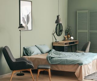 colour drenched green bedroom with wooden floor and bed
